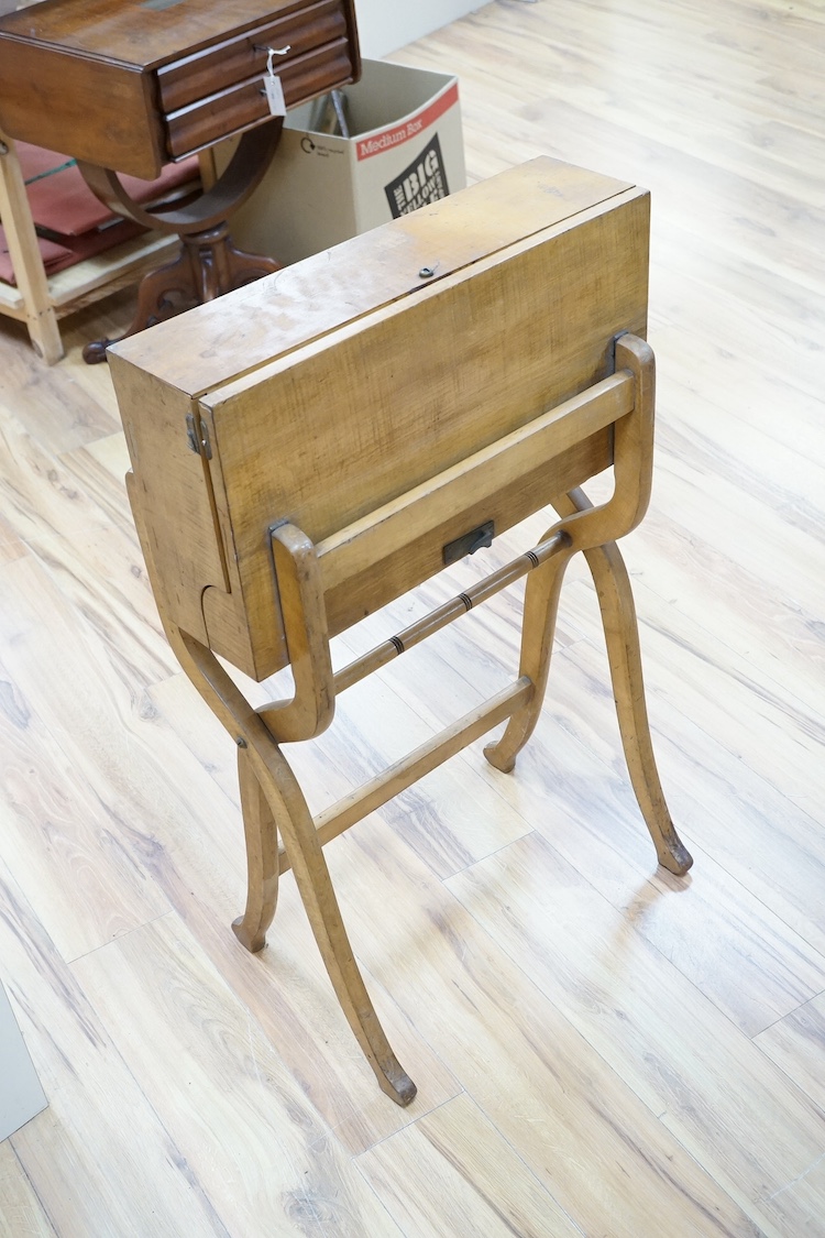 A late 19th century sycamore military folding campaign desk, raised on a trestle stand with X shaped supports, desk section with leather writing surface and folding letter rack, 93cm high, 56cm wide when folded. Conditio